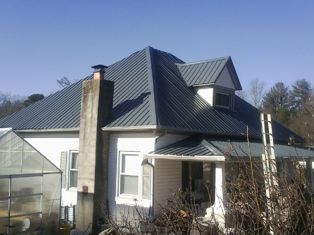 Dark blue standing seam metal roof on a white farmhouse with dormer — Slate & Tile Roof Repair by Roofing Brothers in Keasbey