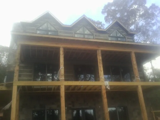 Dormers and porch framing on a large log home under construction — Roof Coating work by our crew in Keasbey