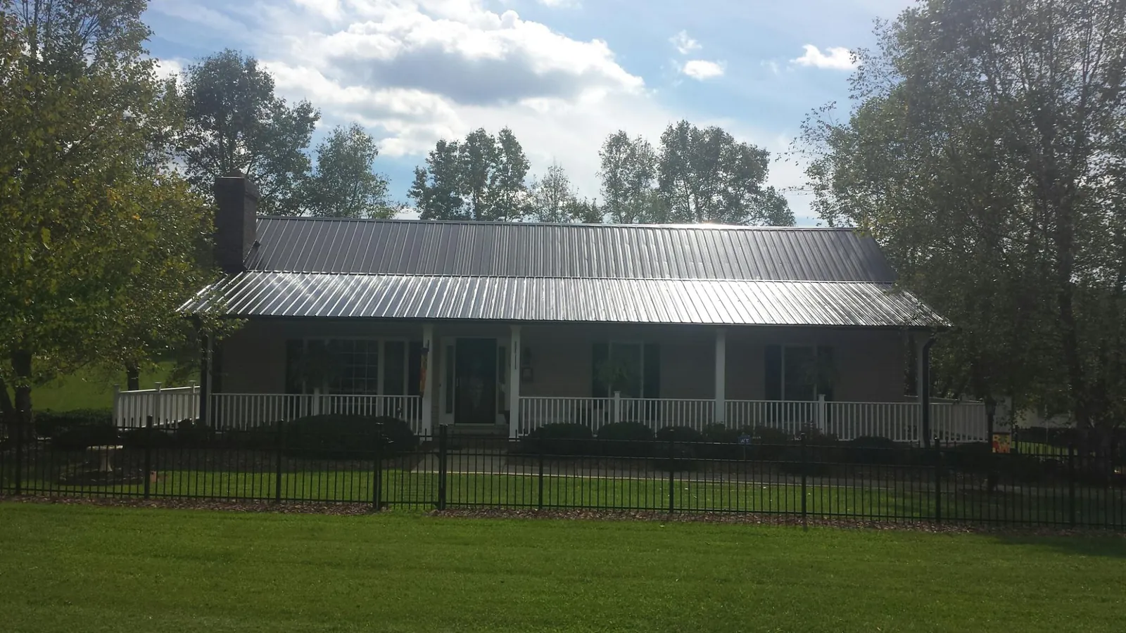 Gray metal roof on a brick ranch with a full width front porch — Gutter Guard Installation work by our crew in Keasbey