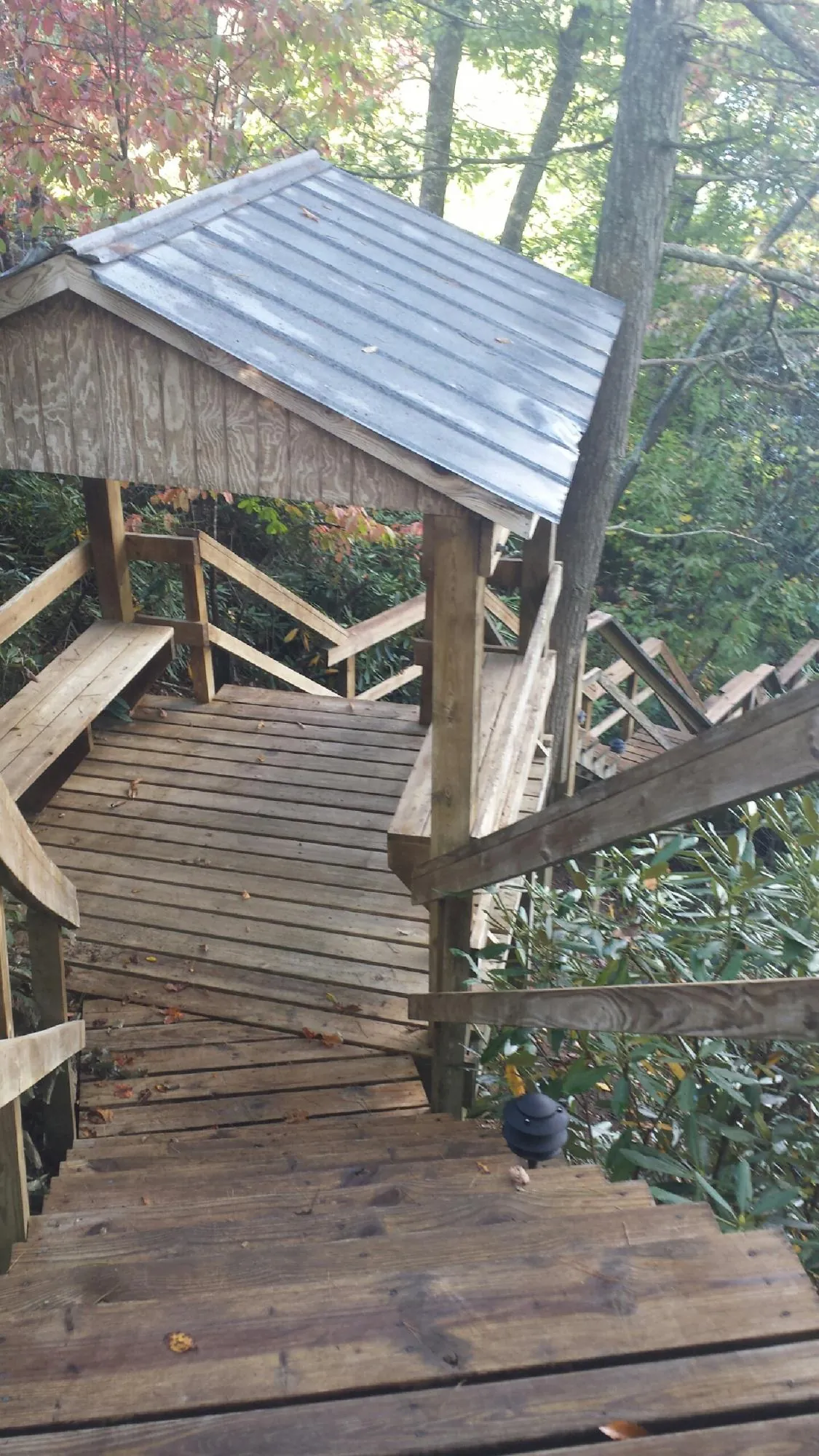 Metal roofed shelter over wooden steps on a wooded walkway — Skylight Repair & Installation work by our crew in Keasbey