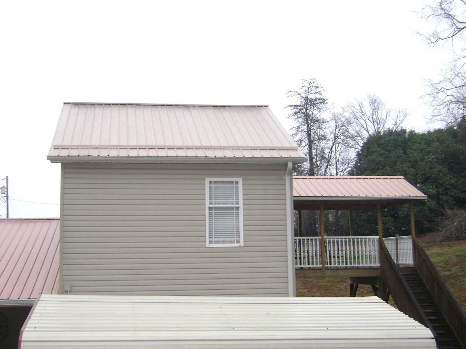 Tan metal roofs on a two story addition and attached porch, from a Roof Replacement job in Keasbey