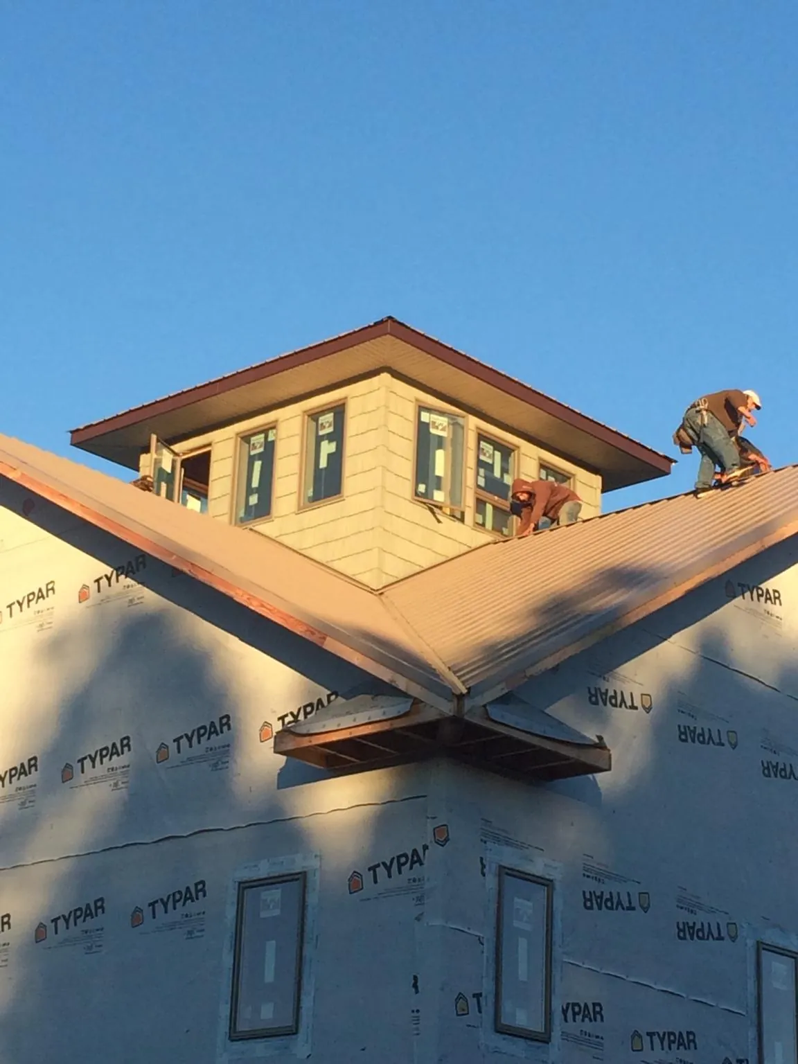 Roofers working around a rooftop cupola on a new metal roof at sunset — Roof Waterproofing in Keasbey by Roofing Brothers